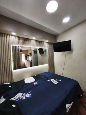 A bedroom with a bed, a mounted TV, a mirror, and a ceiling light. - Mini Suite en Manta (Manta)