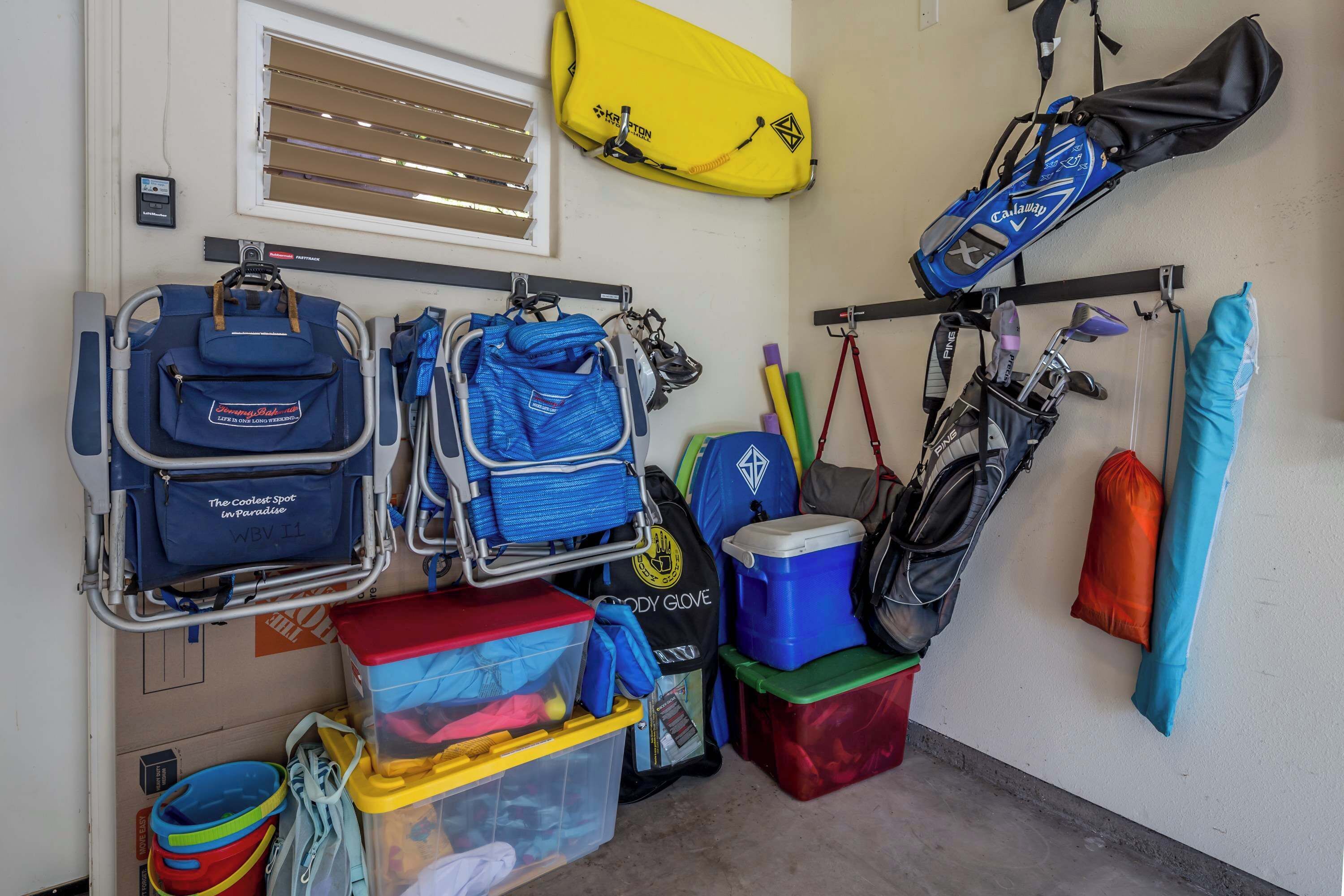Un espace de rangement contenant divers sacs et équipements, notamment des sacs de golf, une combinaison de plongée et un dispositif de flottaison jaune.