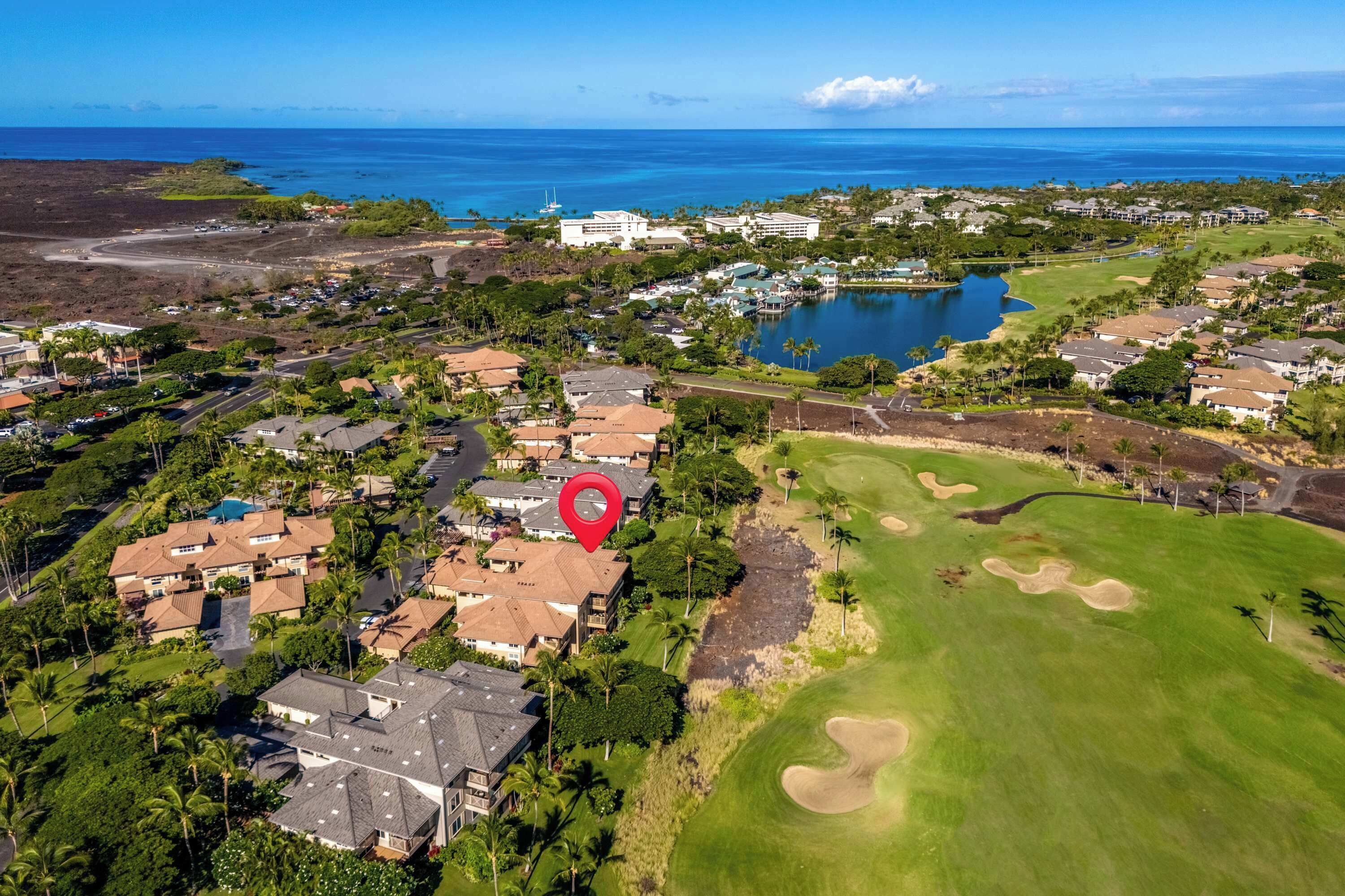A golf course with a large lake, surrounded by residential buildings and a hotel.