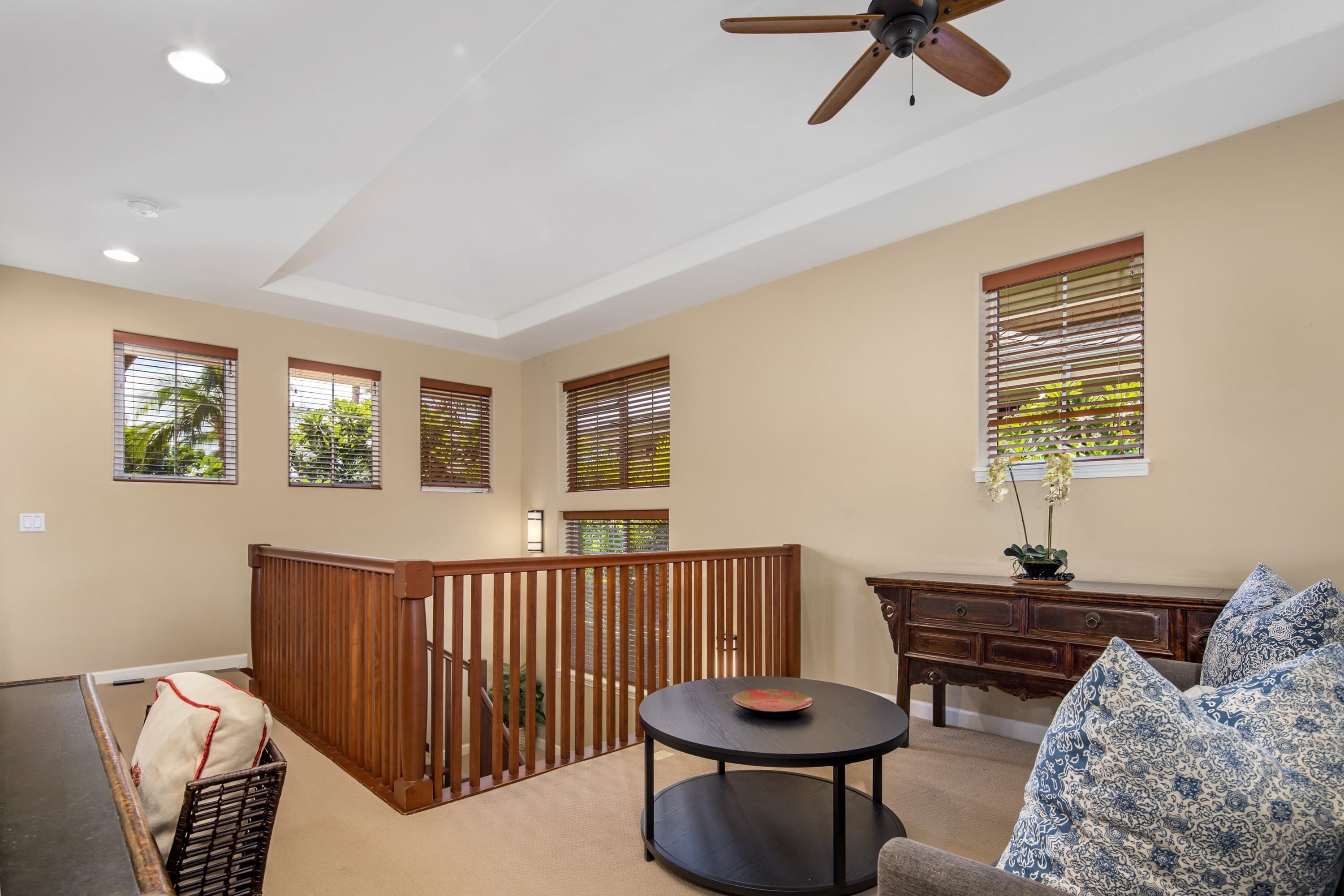 A spacious living area with a wooden balcony, a round table, and a sofa.