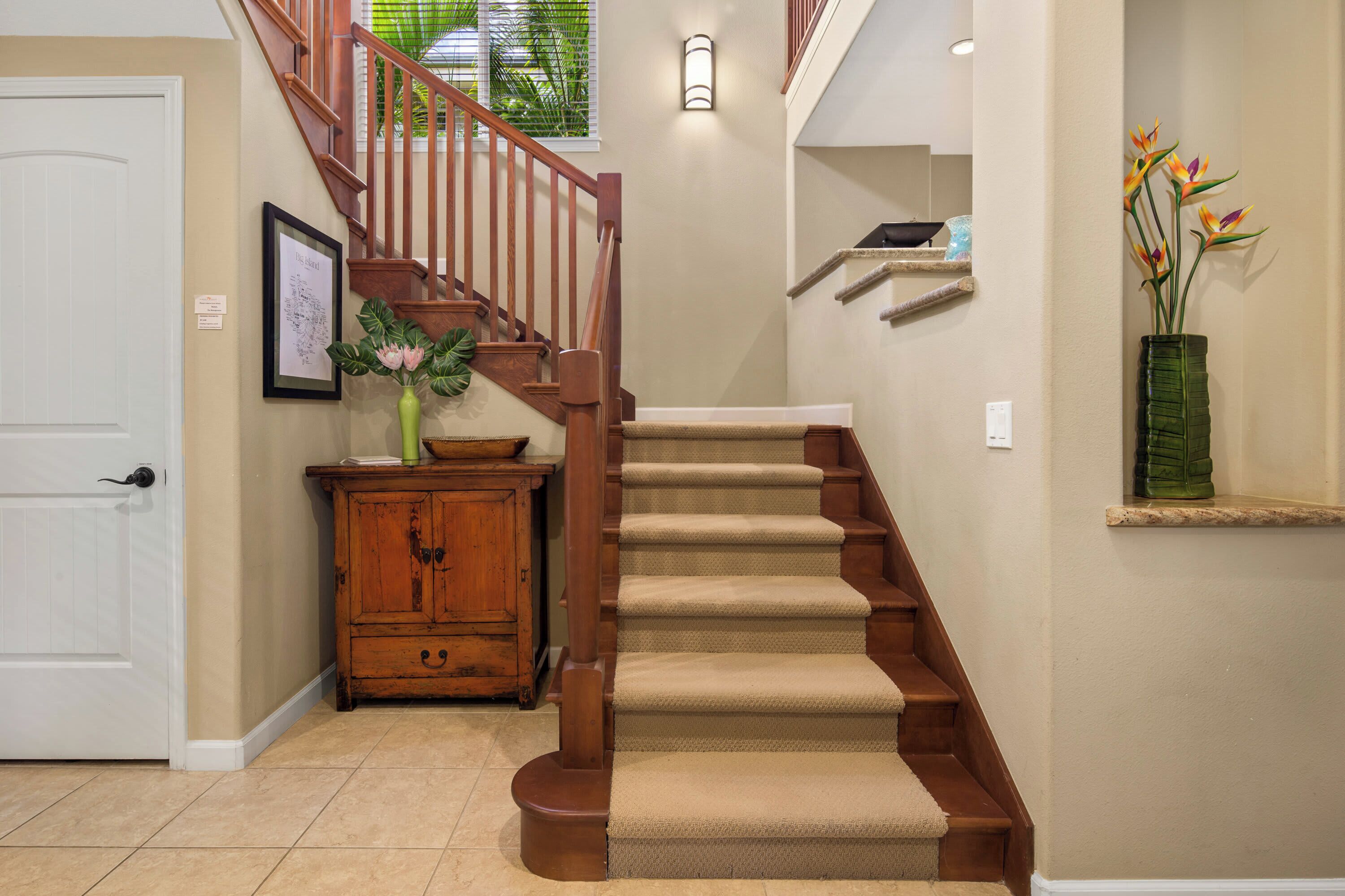 A staircase with a wooden handrail and beige carpeted steps leading to an upper floor.