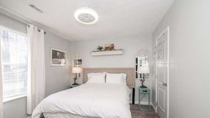 A bedroom with a bed, bedside tables, a nightstand, a wall-mounted shelf, and a door. - Arkstone Retreat 3 - Only 4 minutes to the Ark! (Williamstown)