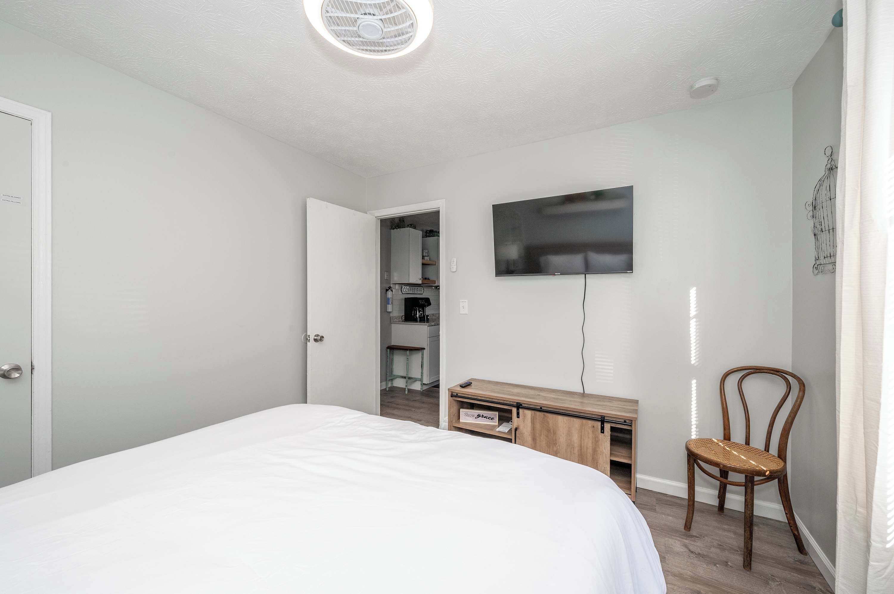 A bedroom with a bed, a desk, a chair, a TV, and a closet.