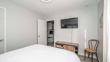 A bedroom with a bed, a desk, a chair, a TV, and a closet.