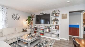 A living room with a sofa, coffee table, TV, bookshelves, and a fireplace.