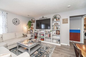 Una sala de estar con sofá, mesa de centro, televisión, estanterías y chimenea.