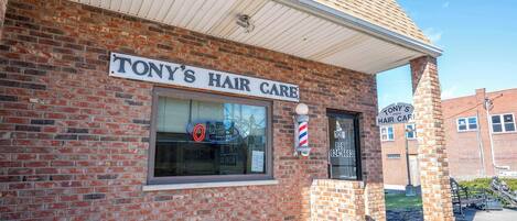 Een bakstenen gebouw met een bord waarop staat 'TONY'S HAIR CARE'.