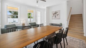 A spacious dining area with a long wooden table, black chairs, and a ceiling fan.