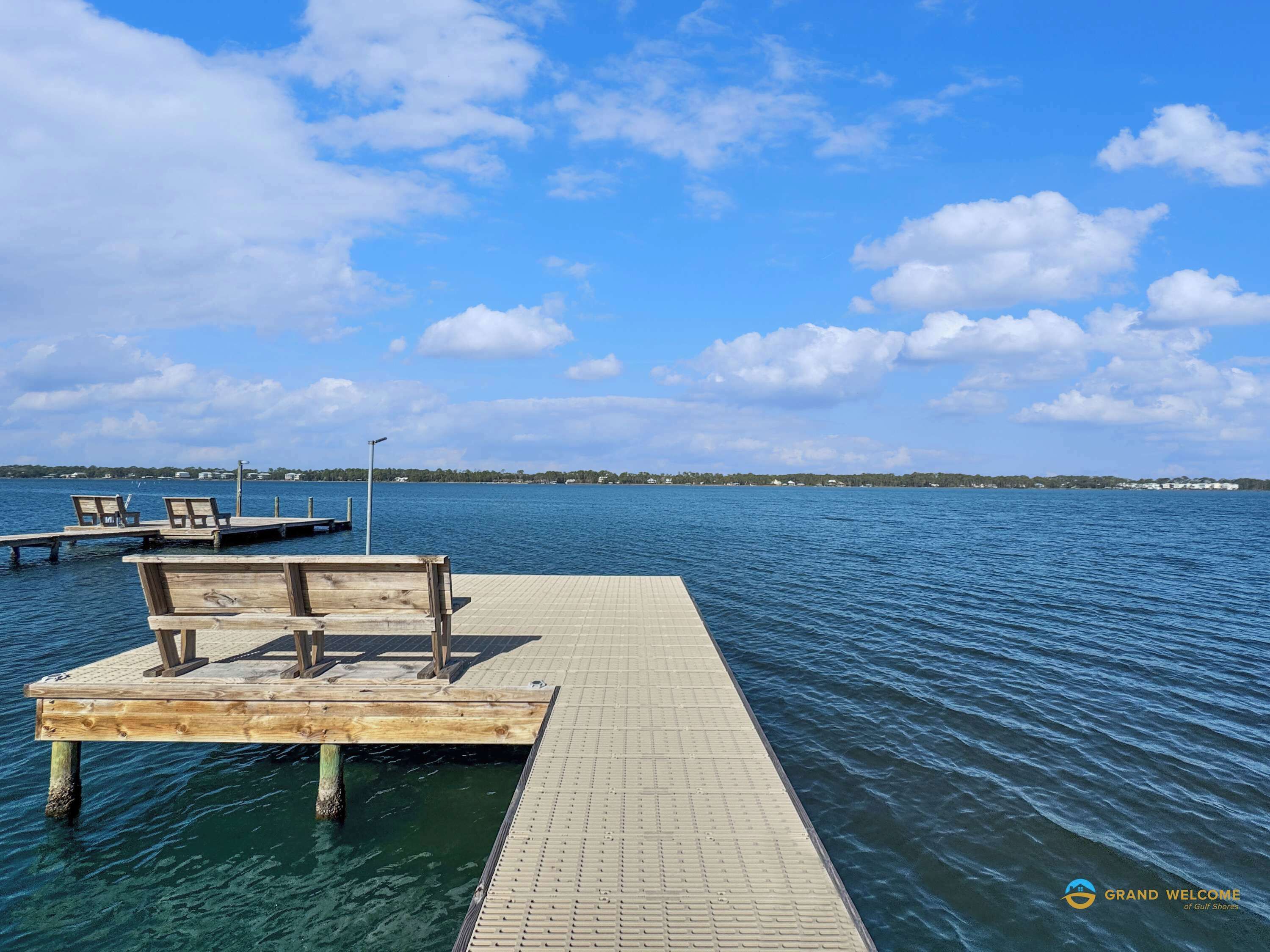 Un moll de fusta que s'allarga sobre una calma aquarel·la, amb bancs i un fanal.