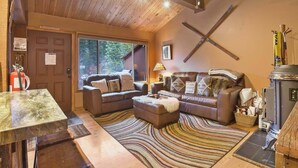 Un salon chaleureux avec une cheminée, des canapés en cuir et un plafond en bois.