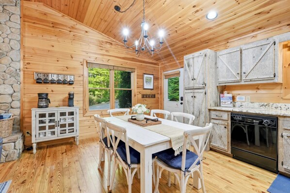 A wooden cabin interior with a dining area, kitchen, and stone wall. - Misty Creek Cabin Private 3 BDR w/ Game Room! (Blue Ridge)