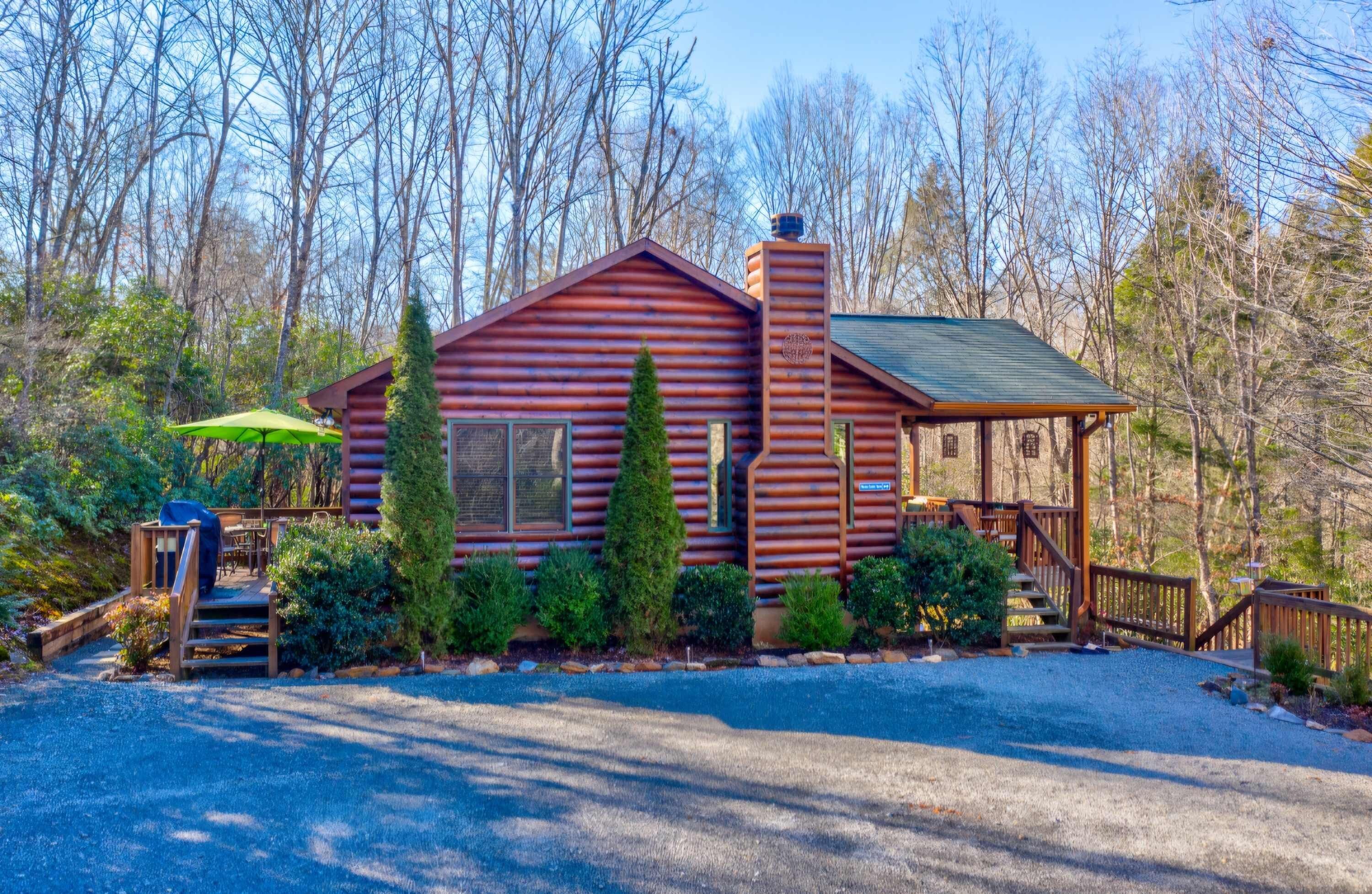 A log cabin with a chimney, a porch, and a covered outdoor seating area.
