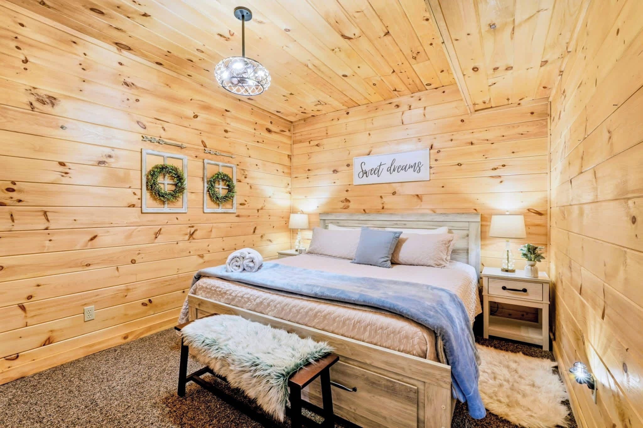 A cozy wooden room with a bed, a bench, and a sign that reads 'Sweet dreams'.