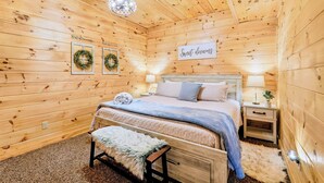 A cozy wooden room with a bed, a bench, and a sign that reads 'Sweet dreams'.