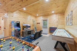A wooden interior with a foosball table, a foosball table with a glass top, a television, and a foosball table with a glass top. - Misty Creek Cabin Private 3 BDR w/ Game Room! (Blue Ridge)
