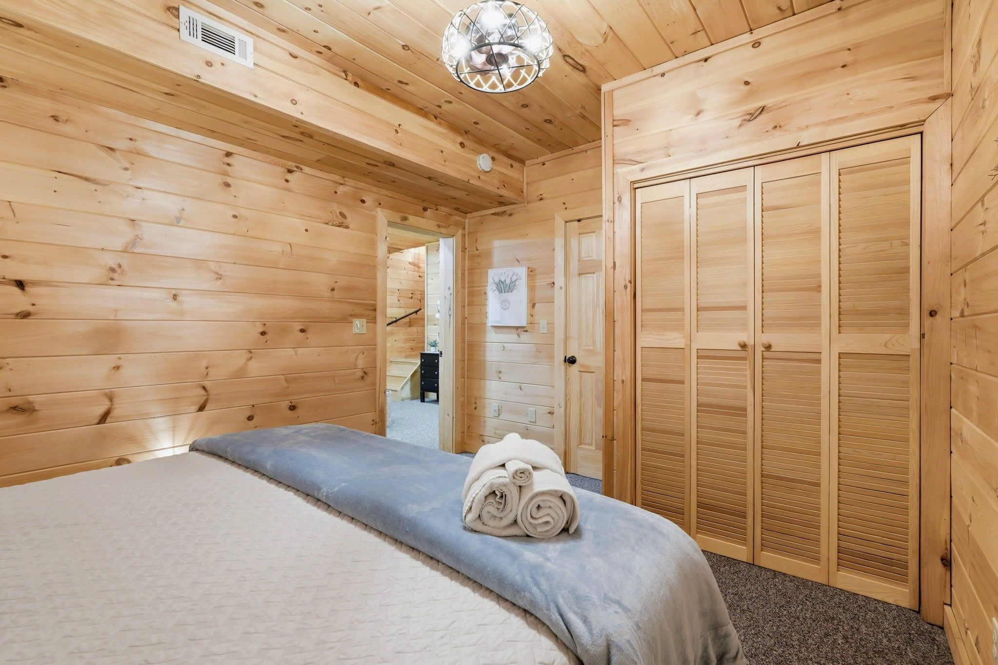 A wooden room with a bed, a set of wooden cabinets, and a door.