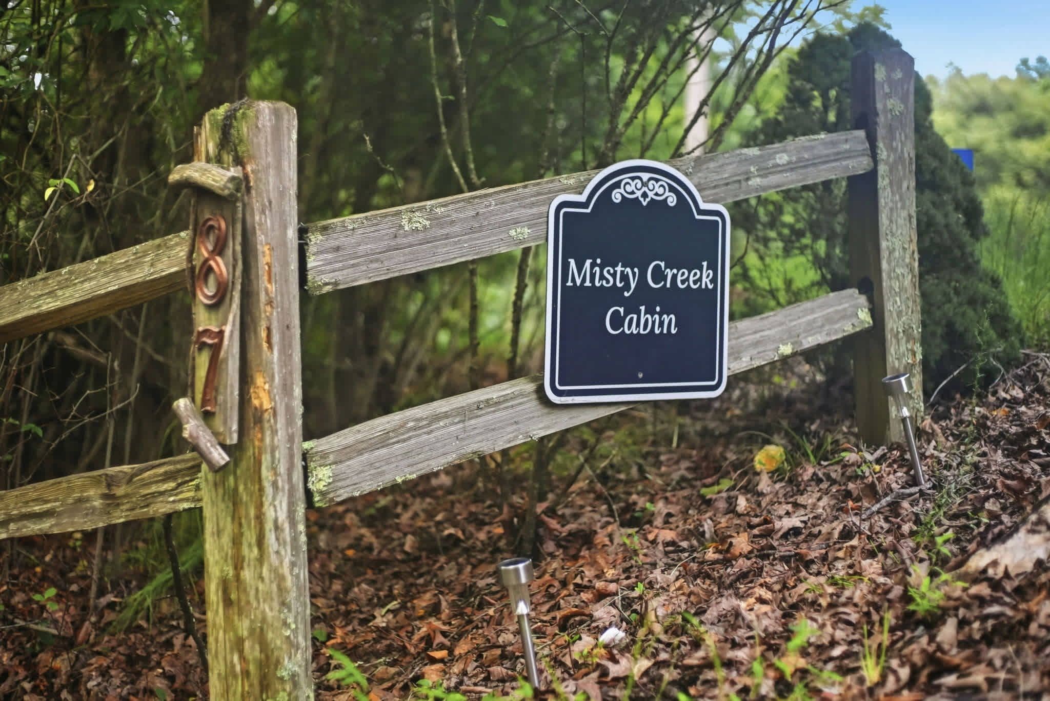 Una verja de madera con un letrero que dice 'Misty Creek Cabin'.