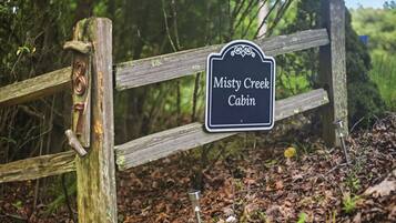 Una verja de madera con un letrero que dice 'Misty Creek Cabin'.