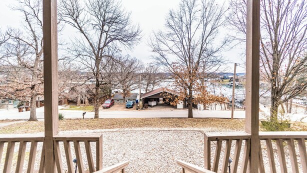 Un porche techado con vista a una zona residencial, con casas y coches aparcados.