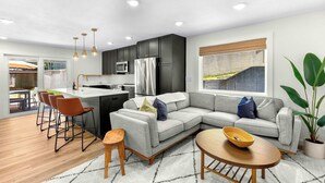 A modern kitchen with dark cabinets, a grey sofa, and a dining area with wooden chairs. - Bearcat Bungalows Two Homes One Rental, Sleep 22 (Gravois Mills)