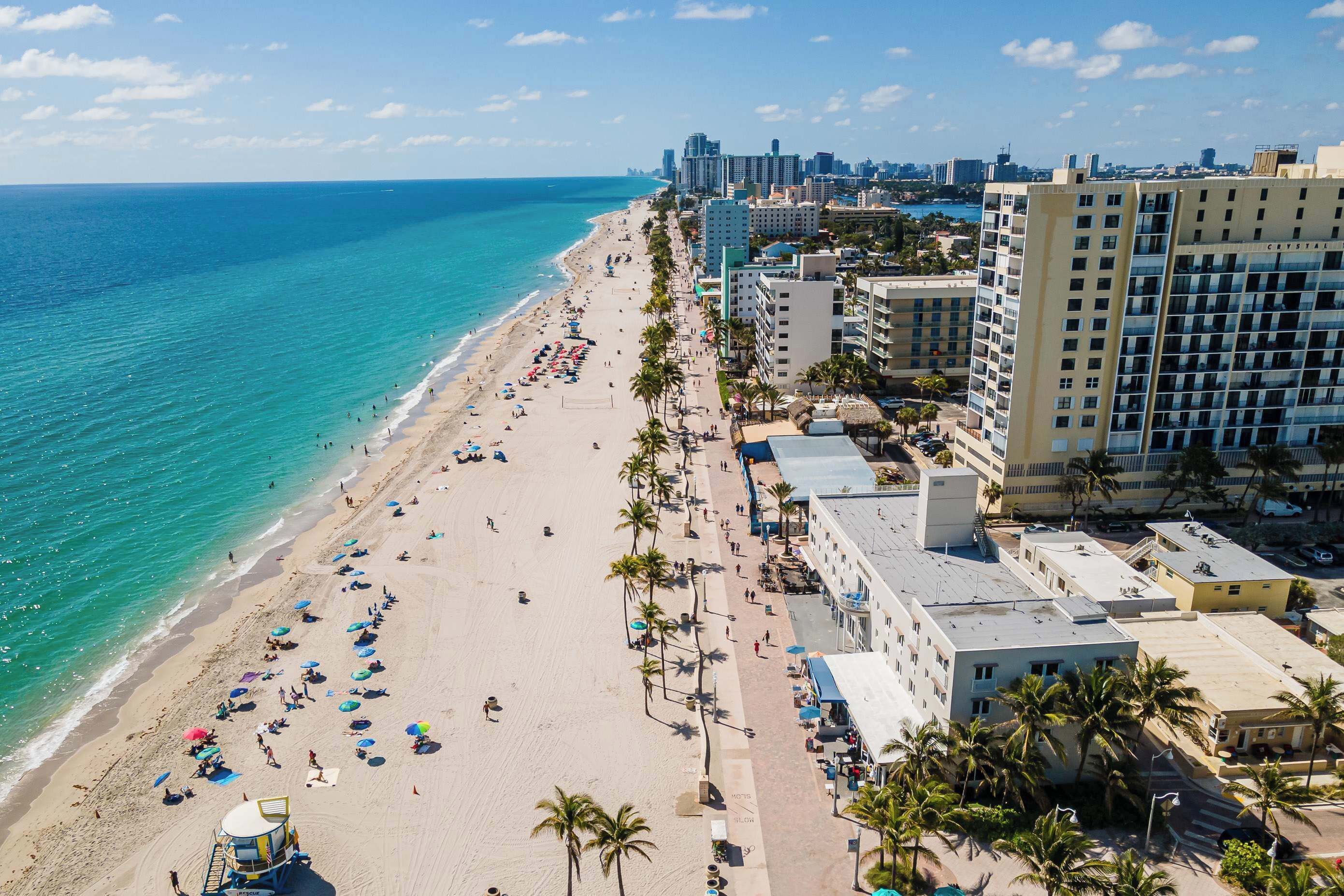 Un paisaje urbano costero con una playa extensa, edificios altos y cielo despejado.