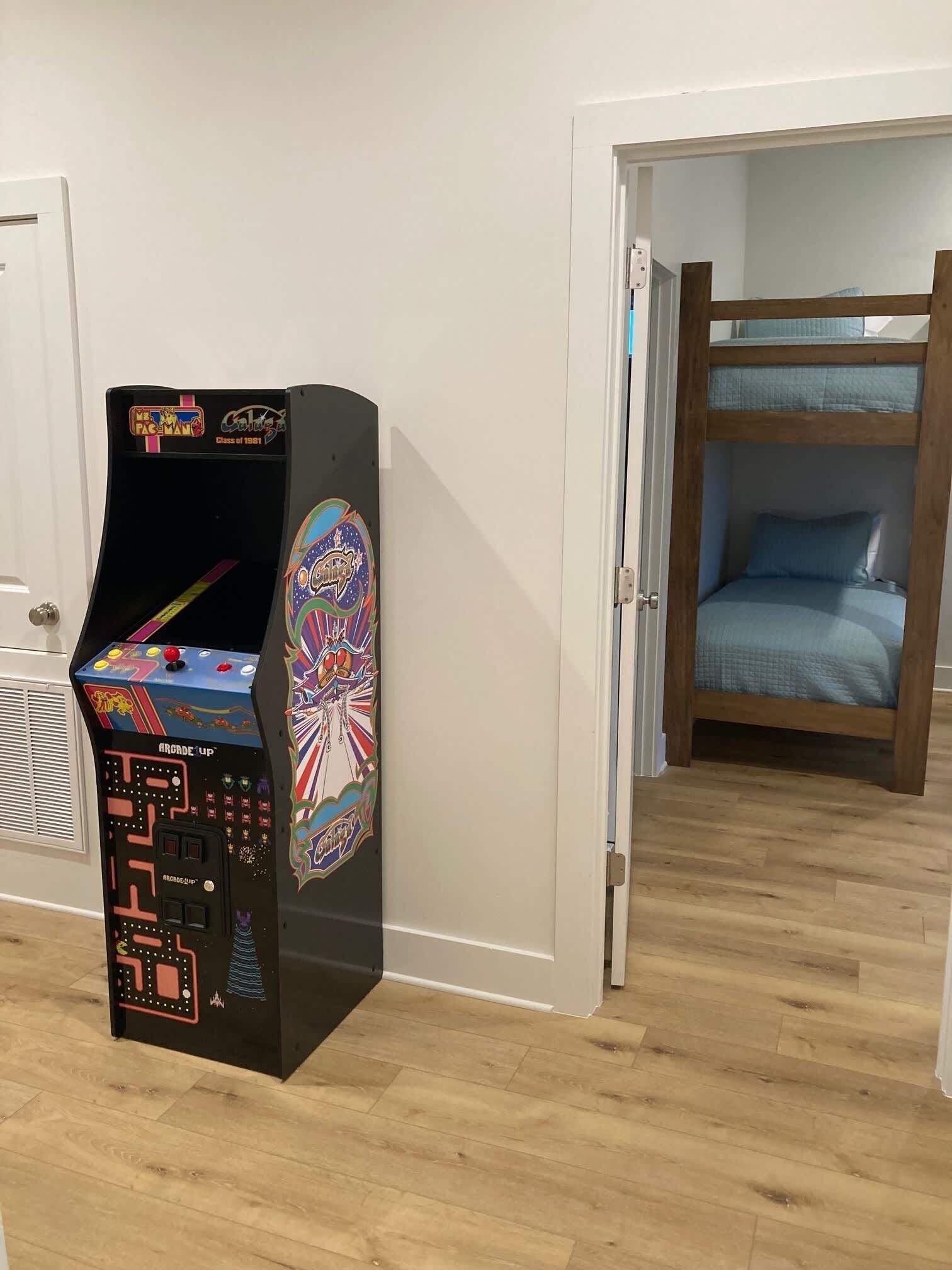 A room with a wooden bunk bed and a vintage arcade machine.