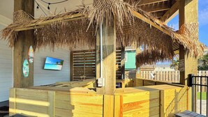 A wooden bar area with a thatched roof, wooden stools, and a television screen on the wall. - 8 Bed 9 Bath Private Pool Grill Walk to Beach (Gulf Shores)