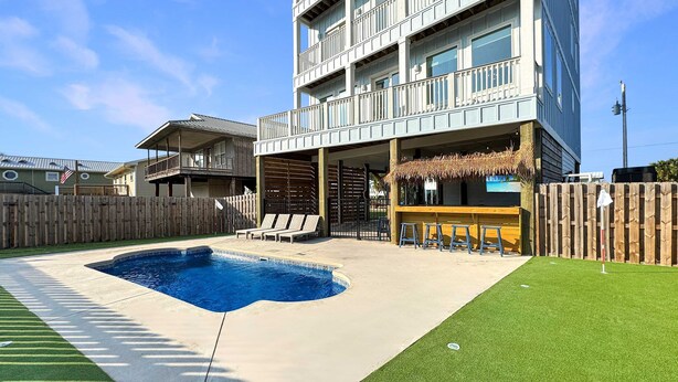 A modern building with a pool, outdoor seating, and a wooden deck. - 8 Bed 9 Bath Private Pool Grill Walk to Beach (Gulf Shores)