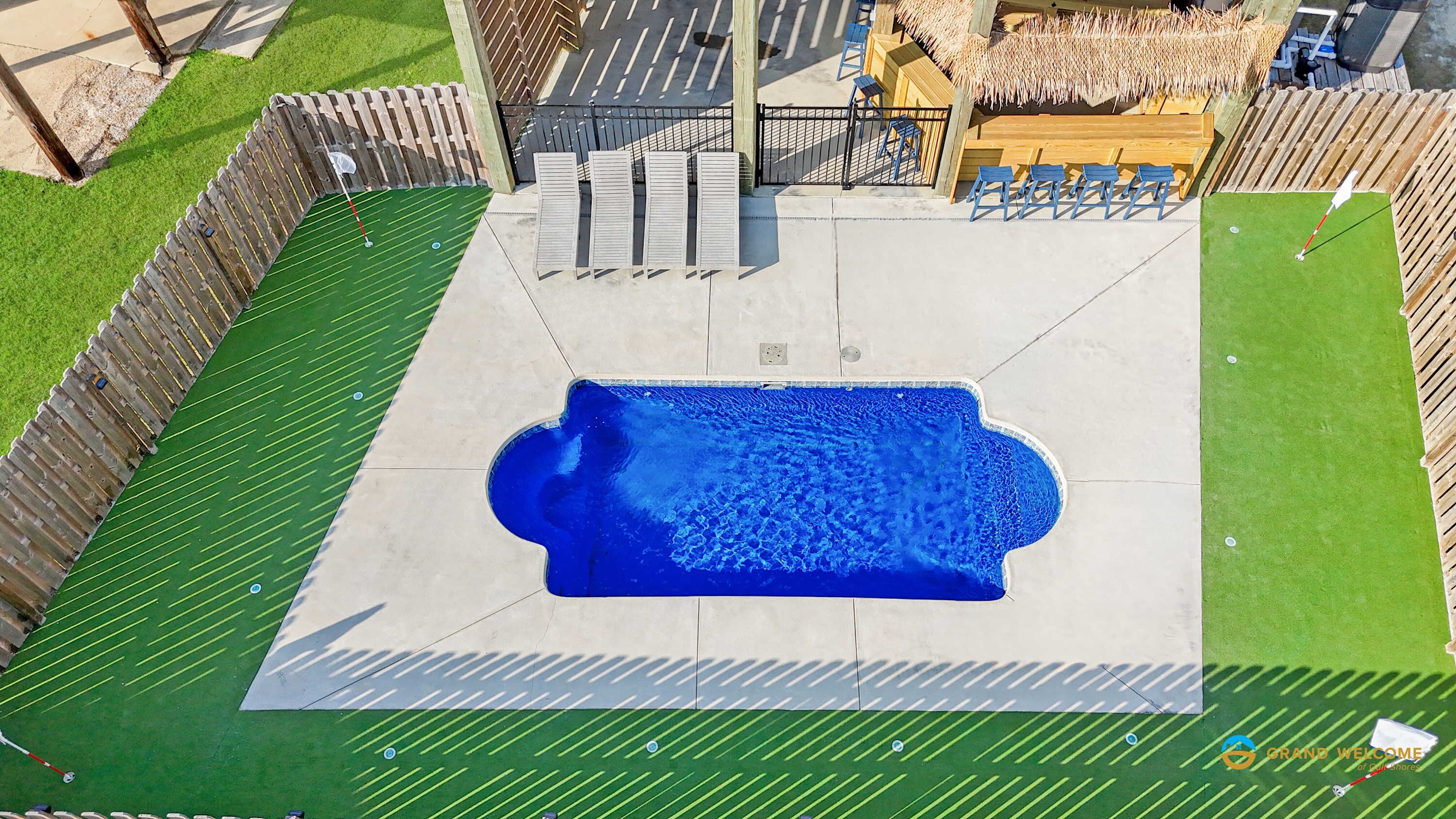 Vista aérea de una piscina con cubierta de madera y sillas de descanso.