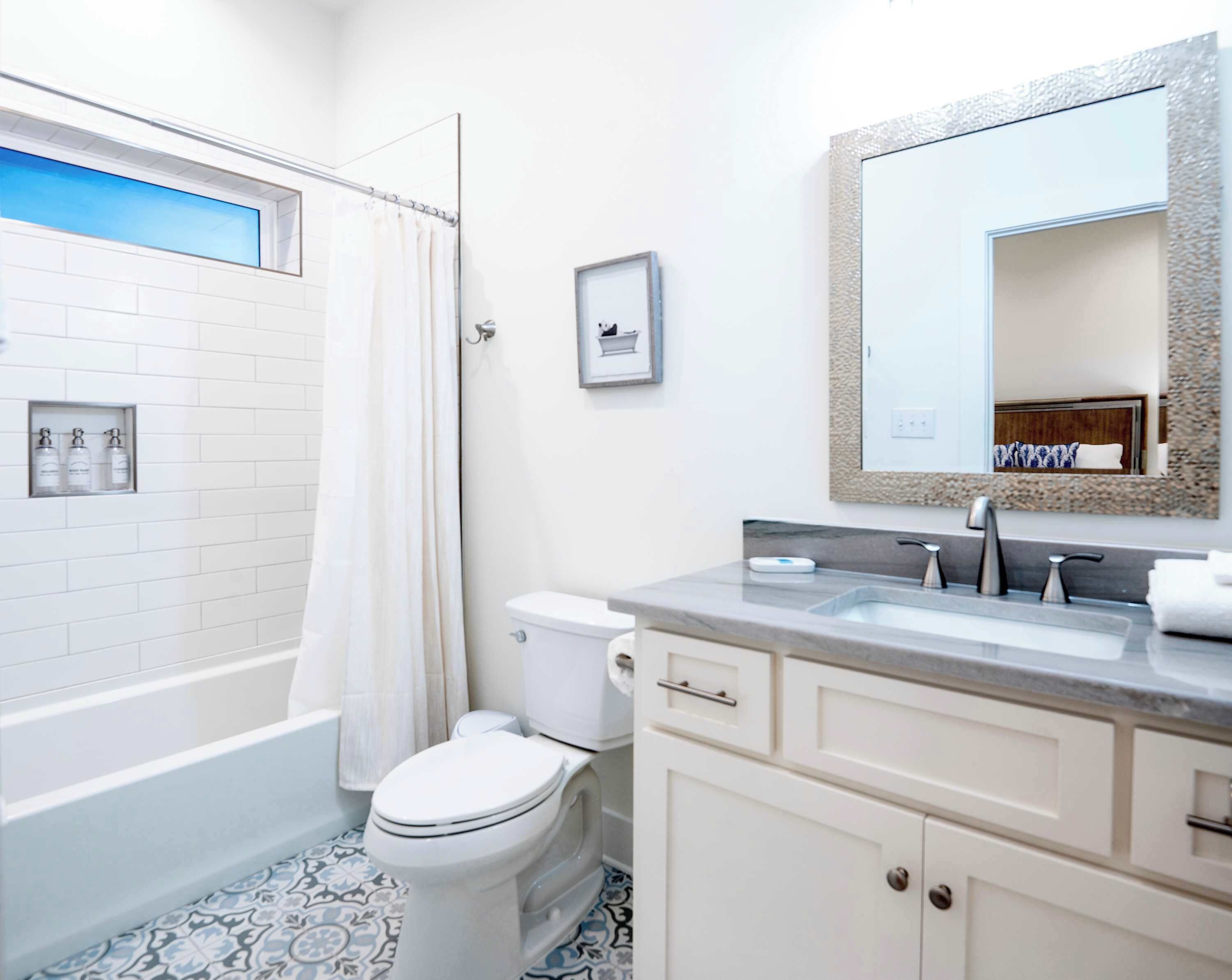Une salle de bain avec une baignoire, des toilettes, un lavabo et un grand miroir.