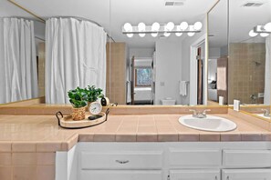 A bathroom with a large mirror, vanity with a sink, and a shower area. - Hikers Hideaway Cozy Resort Condo w/ Pool & More (St. George)