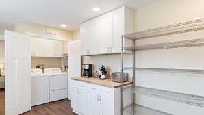 A modern kitchen with white cabinets, a built-in washing machine, a coffee maker, and a toaster. - Diana's Place (Murfreesboro)
