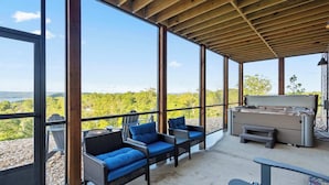 A covered outdoor area with wicker furniture and a barbecue grill.