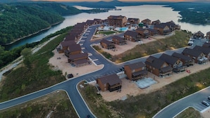 An aerial view of a resort with multiple buildings, a parking lot, and a river.