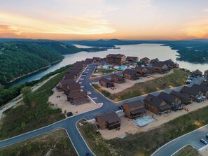 An aerial view of a resort with multiple buildings, a parking lot, and a river. - A Birds Eye Bridge View - 5 BDR w/ Private Hot Tub (Kimberling City)