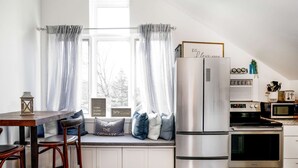Una cucina moderna con una panca integrata, elettrodomestici in acciaio inossidabile e una finestra con tende leggere.