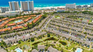 A coastal residential area with multiple apartment buildings, a central swimming pool, and a view of the ocean. - The Turtle Nest Resort Condo w/ Pool! (Panama City Beach)
