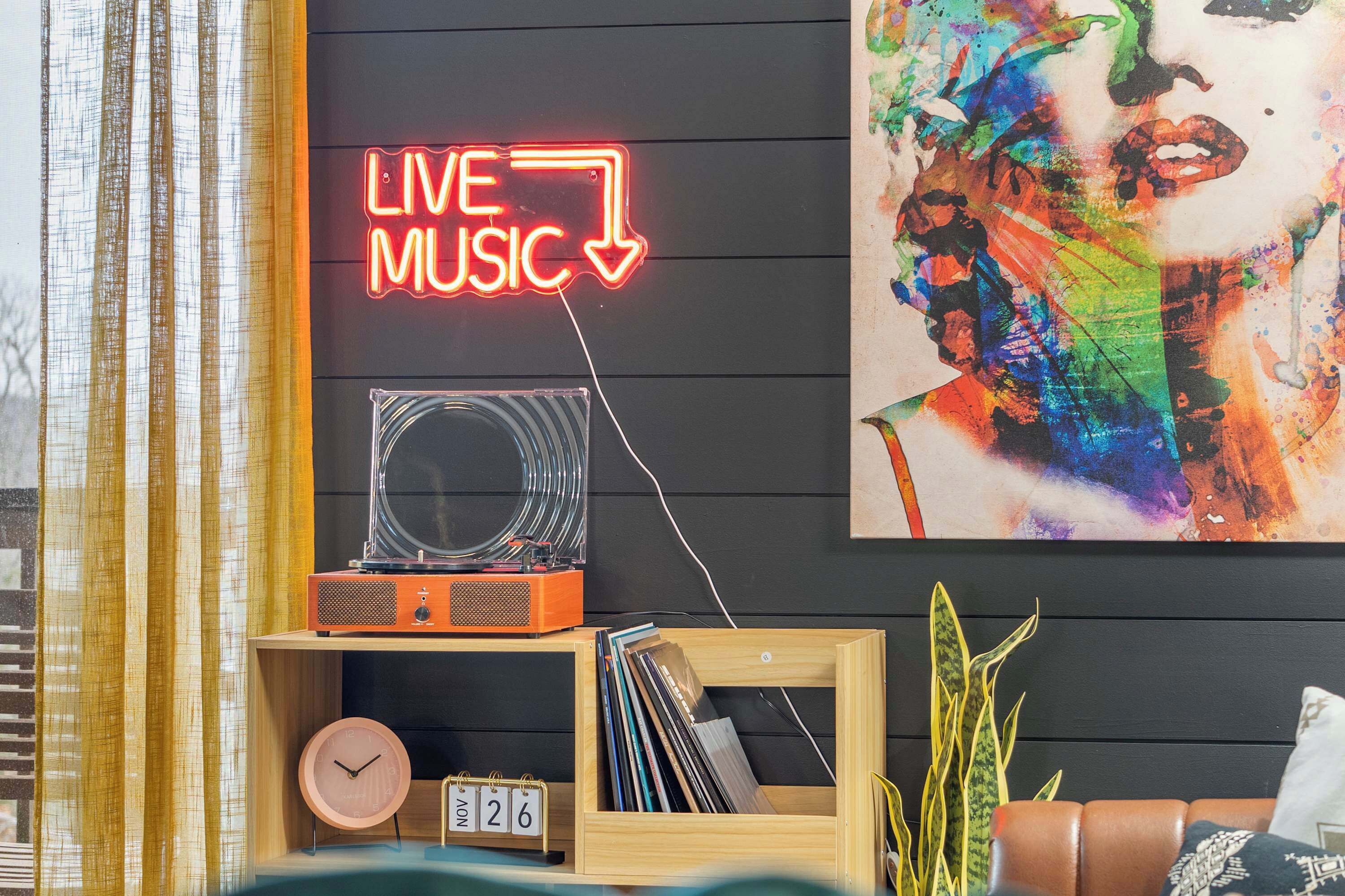A room with a neon sign reading "LIVE MUSIC", a vintage radio, a clock, and a calendar on a wooden shelf.