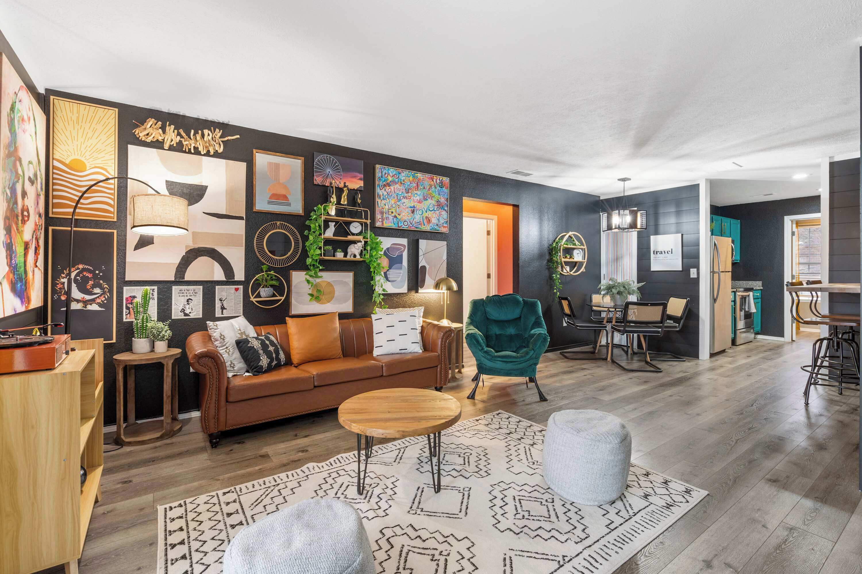A modern living room with a brown leather sofa, a round wooden coffee table, and a teal armchair.