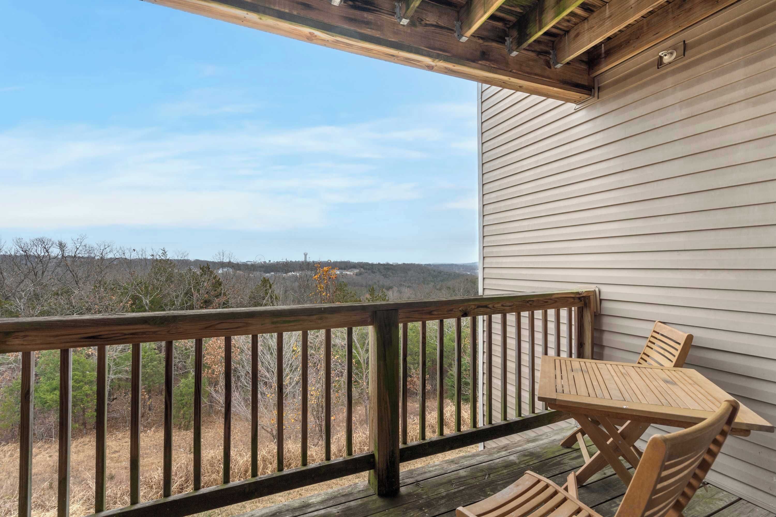 Eine Holzterrasse mit Tisch und Stühlen mit Blick auf eine bewaldete Landschaft.