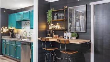 Una cocina moderna con gabinetes azul verdosos, una barra de madera y taburetes de bar.