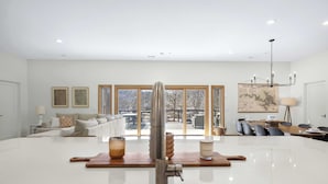 A spacious kitchen with a central island, large windows, and a dining area with a view. - Big Bear Bungalow Stay on Ozark Waterfront (Gravois Mills)