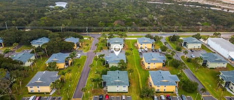 Una vista aerea di una zona residenziale con diverse case a due piani, una strada centrale e un parcheggio.