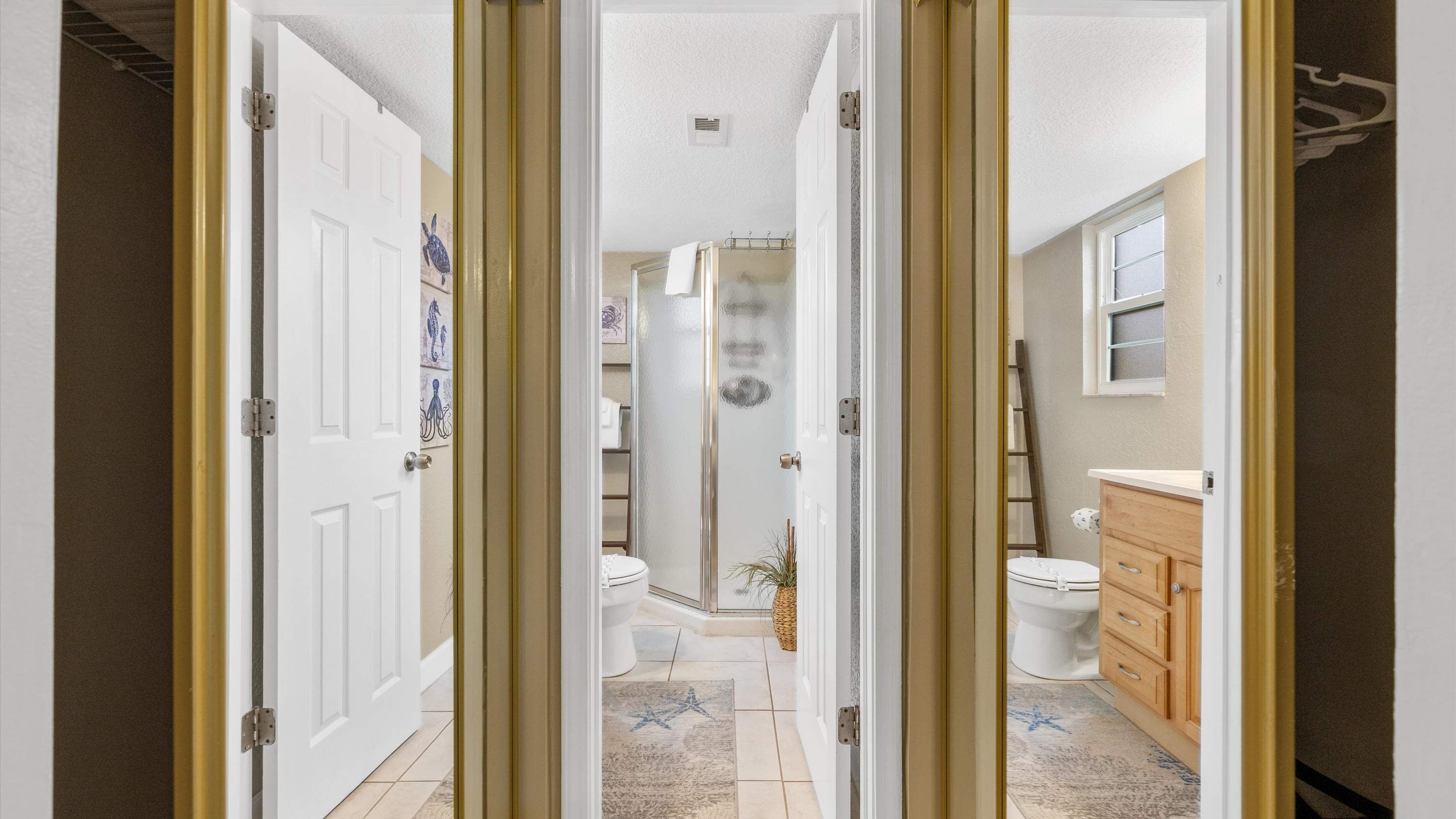 A hallway leading to a bathroom with a shower, toilet, and vanity.