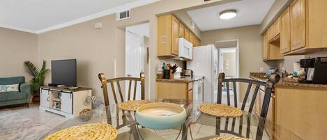 Un espacio habitable compacto con zona de comedor, kitchenette y televisor.