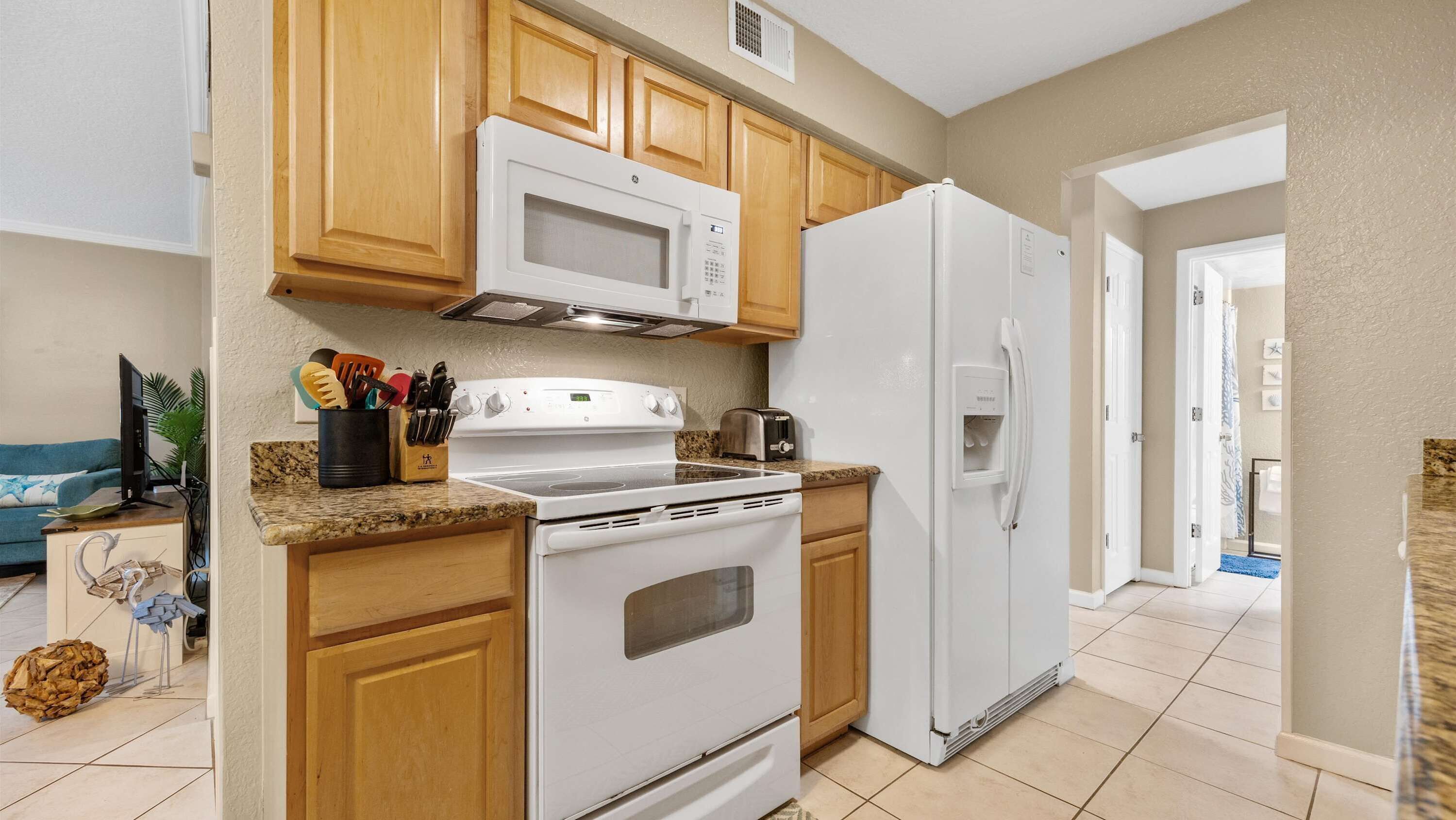 A kitchen with wooden cabinets, a microwave, a stove, and a refrigerator.