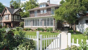 A two-story house with a large front window, a white picket fence, and a well-maintained lawn. - Its Showtime Historic Downtown Geneva Escape! (Lake Geneva)