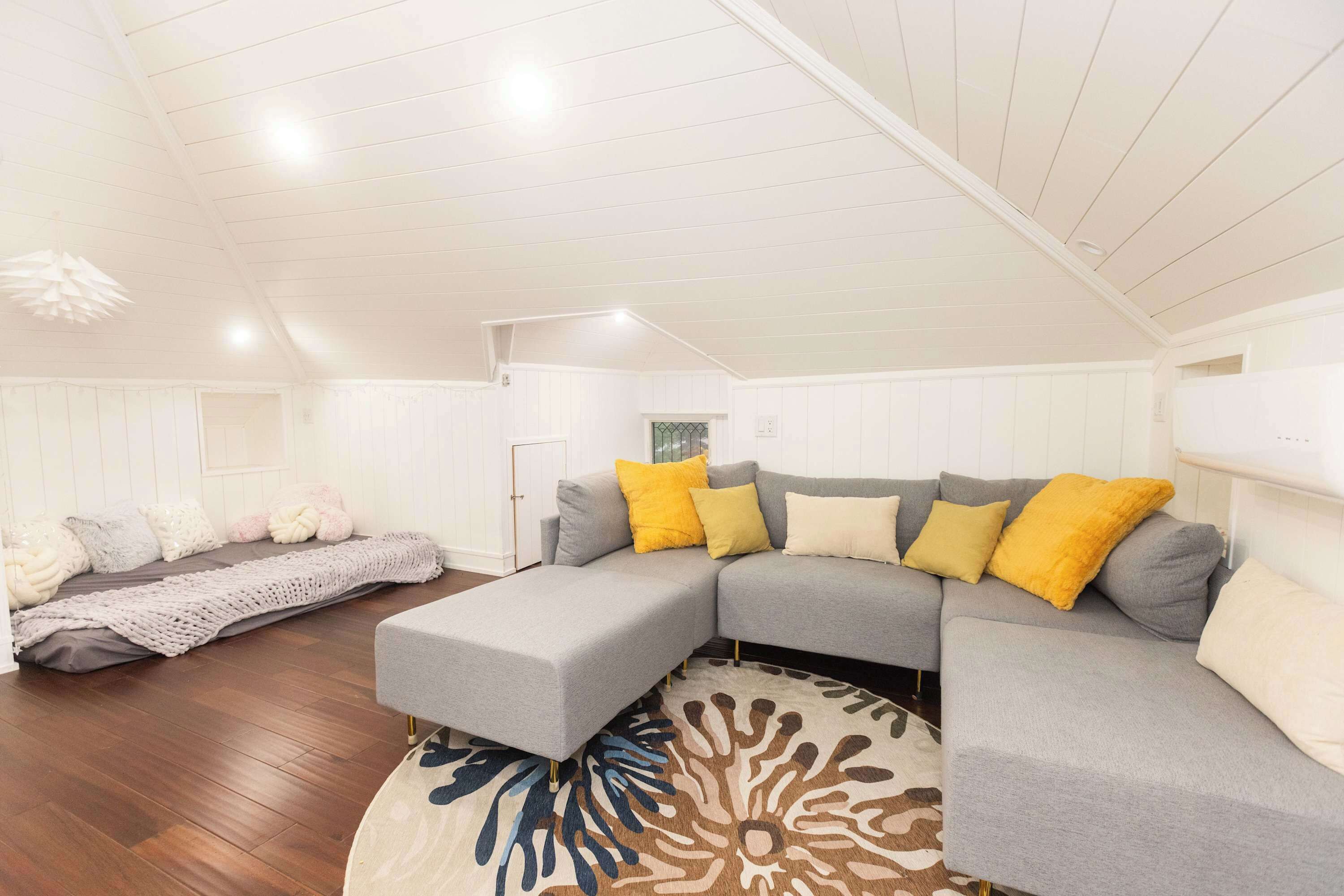 A spacious living room with a large sectional sofa, a patterned rug, and wooden flooring.