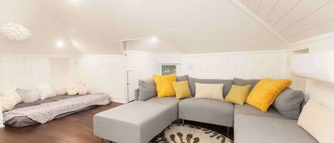 A spacious living room with a large sectional sofa, a patterned rug, and wooden flooring.