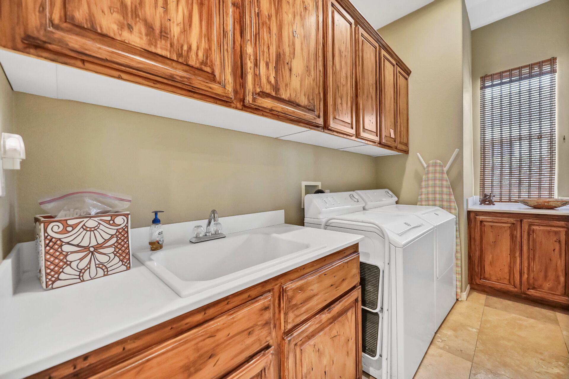 A laundry room with wooden cabinets, a washing machine, and a sink.